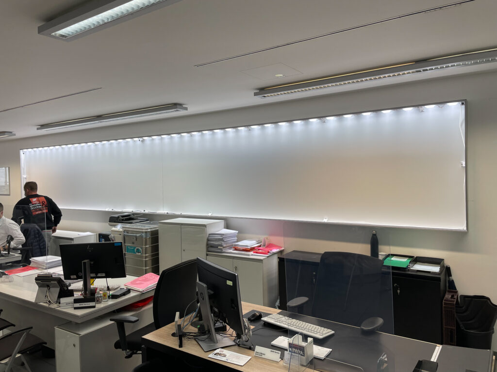 Leuchtkasten mit beleuchtetem Hintergrund im Büro der ISLINGER GmbH, umgeben von Büromöbeln.