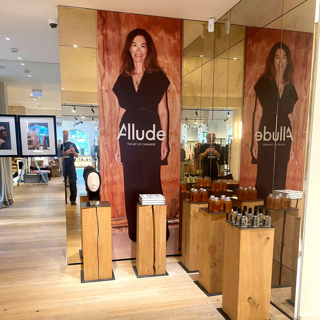 Präsentation der Marke Allude mit einer großen Wandgrafik und Produkten in einem Geschäft.