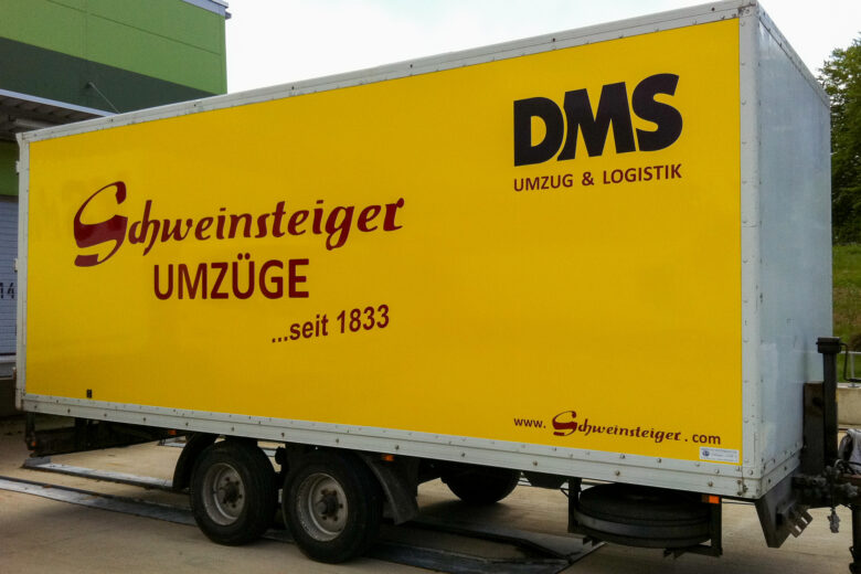 Gelber Umzugswagen mit der Aufschrift 'Schweinsteiger Umzüge' und 'DMS Umzug & Logistik'.