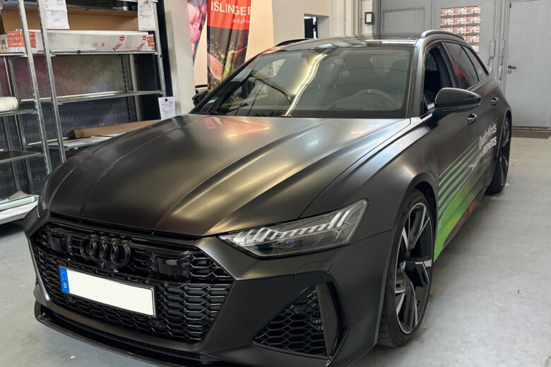 Audi A6 mit mattschwarzer Folierung und grünen Akzenten in einem Innenraum.