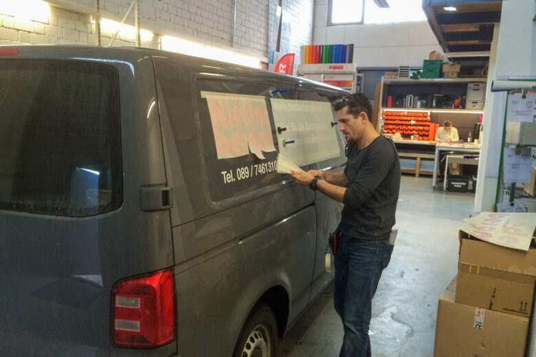 Ein Mann, der eine Folierung auf einem VW T5 Lieferwagen anbringt.