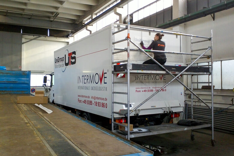 Lkw mit Folierung von Intermove, während eine Person auf einem Gerüst arbeitet.