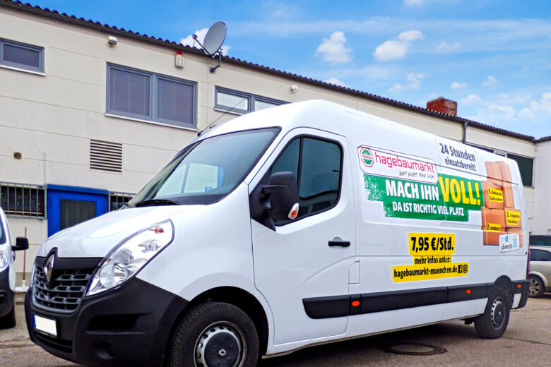 Weißer Lieferwagen von Hagebaumarkt mit Werbung auf der Seite, geparkt vor einem Gebäude.