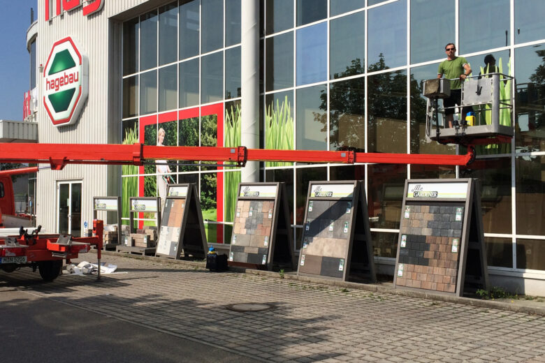 Außenansicht des Hagebau-Marktes mit Musterplatten zur Auswahl, Mitarbeiter auf einer Hebebühne.