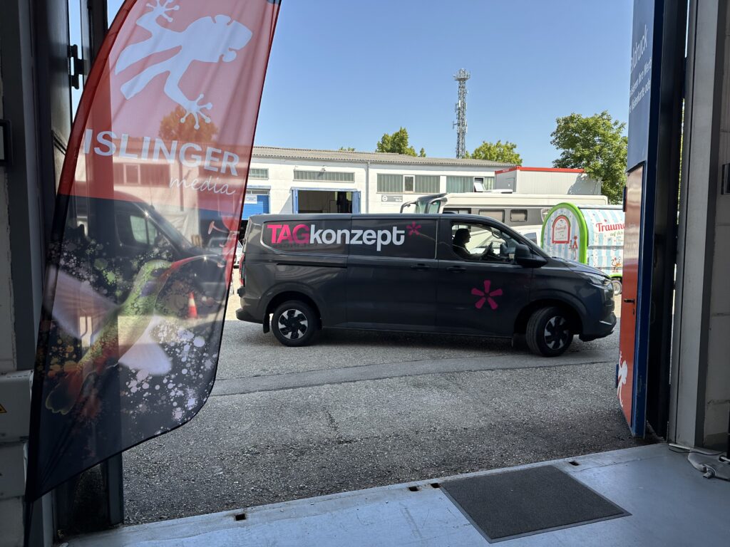 Schwarzes Fahrzeug der ISLINGER GmbH mit TAGkonzept-Logo, das durch ein Tor fährt.