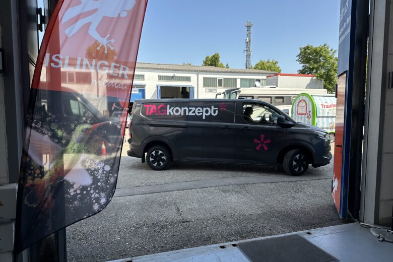 Schwarzes Fahrzeug der ISLINGER GmbH mit TAGkonzept-Logo, das durch ein Tor fährt.