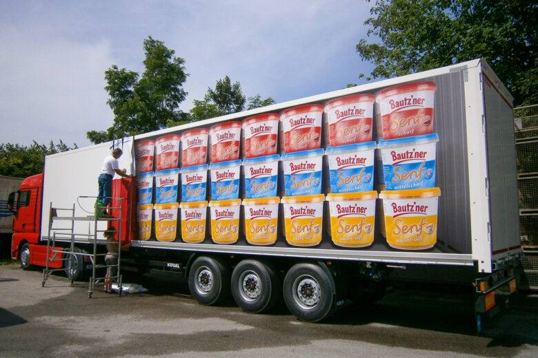 Lkw mit bunten Werbeaufdrucken von Bautzner Senf auf der Ladefläche.