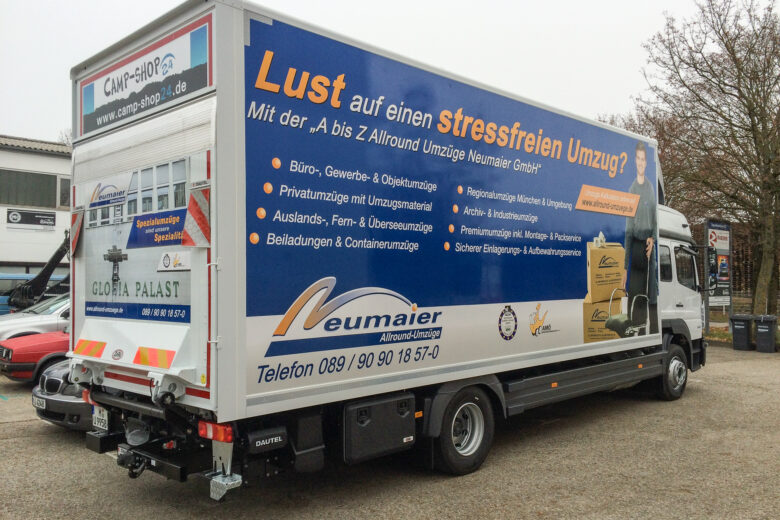 Lkw von Neumaier mit Werbung für Umzugsdienstleistungen und Kontaktdaten auf der Seite.