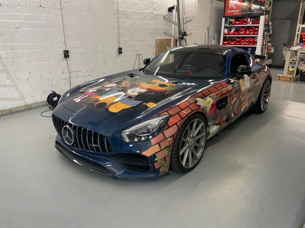 Mercedes-AMG mit einer bunten Comic-Folierung, die verschiedene Charaktere darstellt.