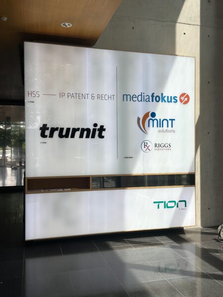 Leuchtkasten mit den Logos von trurnit, mediafokus, mint solutions, RIGGS executives und TION.