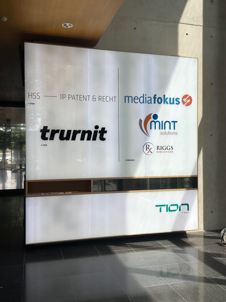 Leuchtkasten mit den Logos von trurnit, mediafokus, mint solutions, RIGGS executives und TION.