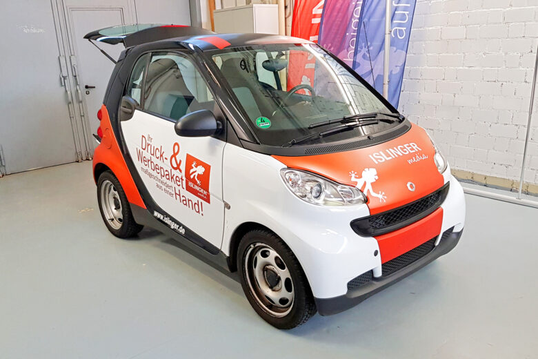 Ein Smart Auto mit ISLINGER-Beschriftung in Rot und Weiß, platziert in einem Innenraum.