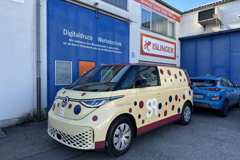 Volkswagen SmartRail Fahrzeug in gelb mit roten und schwarzen Punkten vor einem Gebäude von ISLINGER GmbH.