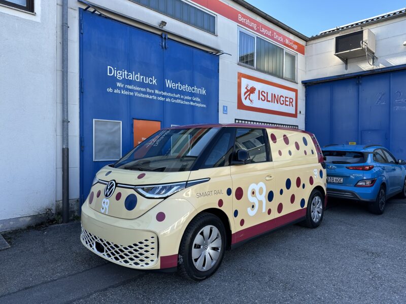 Volkswagen SmartRail Fahrzeug in gelb mit roten und schwarzen Punkten vor einem Gebäude von ISLINGER GmbH.