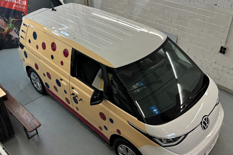Volkswagen Transporter mit einem bunten Design, das runde Punkte in verschiedenen Farben zeigt.