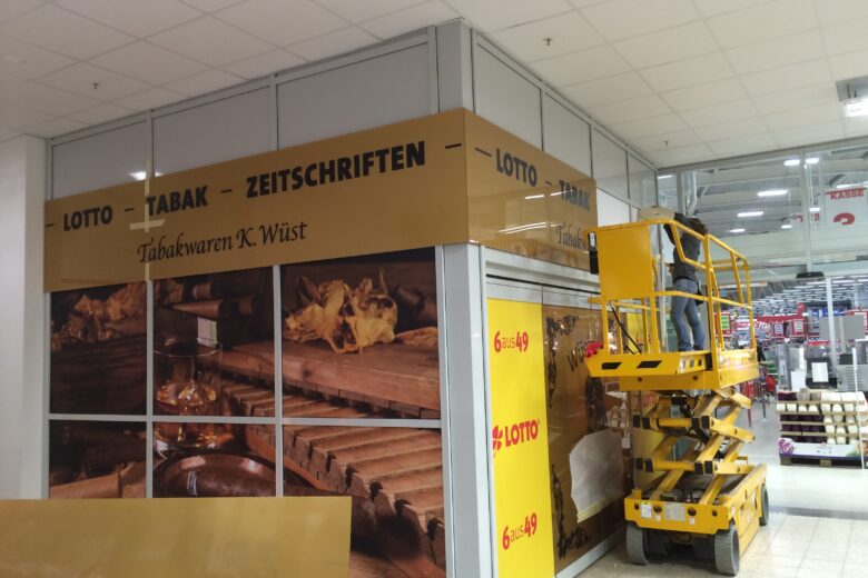 Ein Mitarbeiter montiert ein Schild für das Tabakwaren-Geschäft K. Wüst in einem Verkaufsraum.