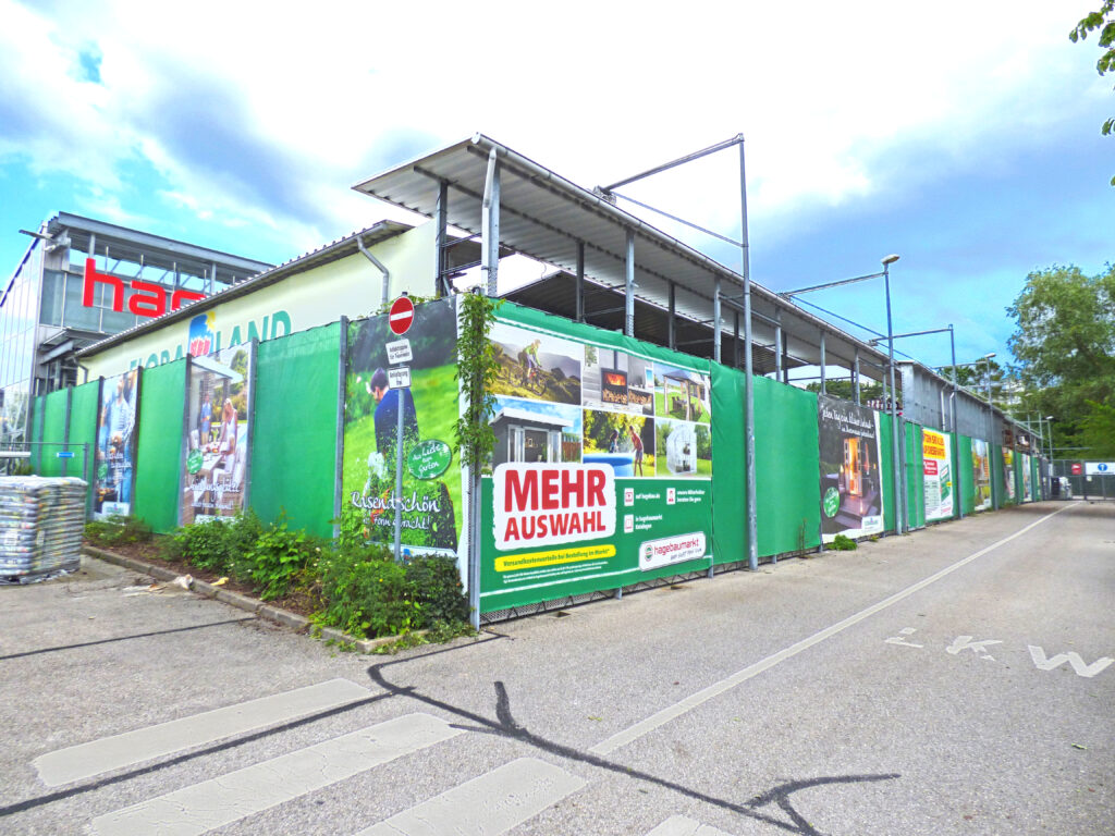 Werbeplanen mit verschiedenen Designs und Texten am Hagebaumarkt-Gelände.