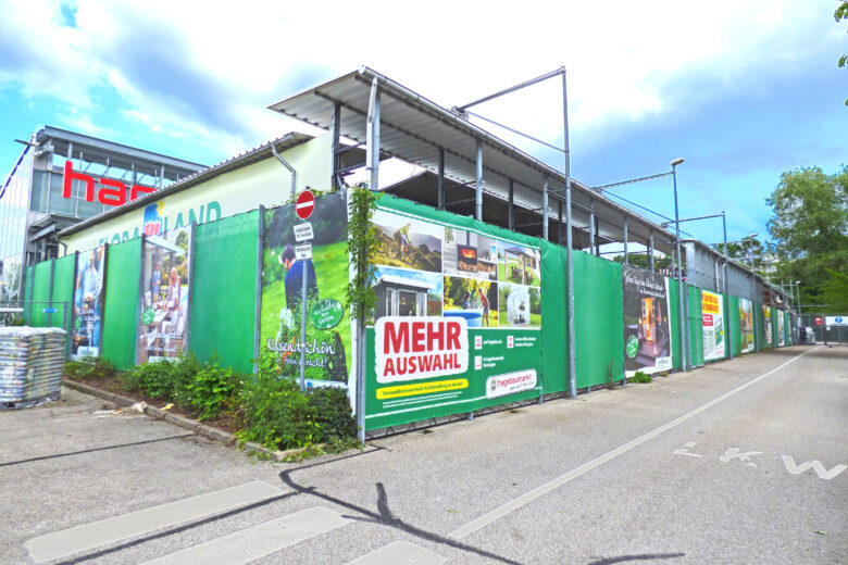 Werbeplanen mit verschiedenen Designs und Texten am Hagebaumarkt-Gelände.