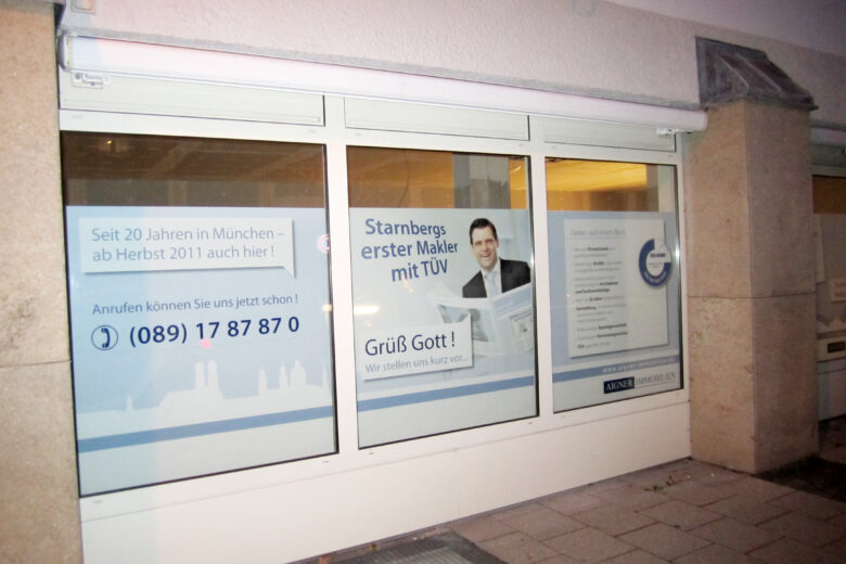 Schaufenster eines Maklerbüros in München mit Informationen und Kontaktdaten.