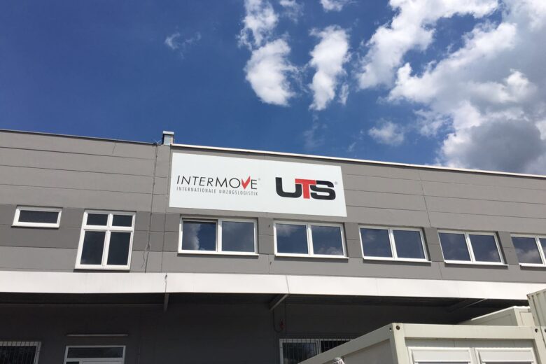 Signage of INTERMOVE and UTS on a building exterior with a blue sky.