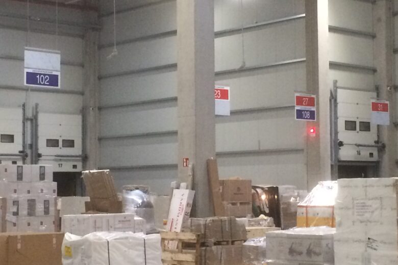Lagerbereich mit Paletten und Regalen, nummeriert mit Schildern 23, 27, 102, 108 und 311.