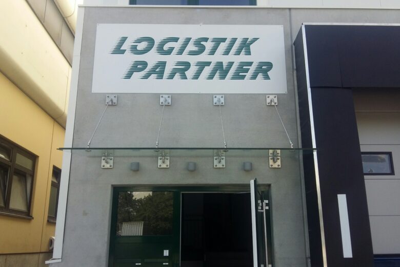 Firmenschild mit der Aufschrift 'LOGISTIK PARTNER' an einem Gebäude mit moderner Architektur.