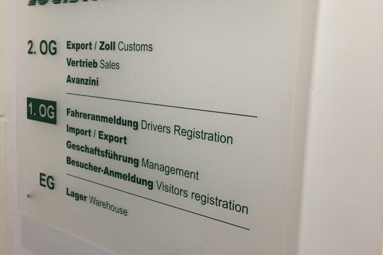 Transparente Beschilderung mit Informationen zu Logistikpartner-Diensten wie Export, Zoll und Lager.