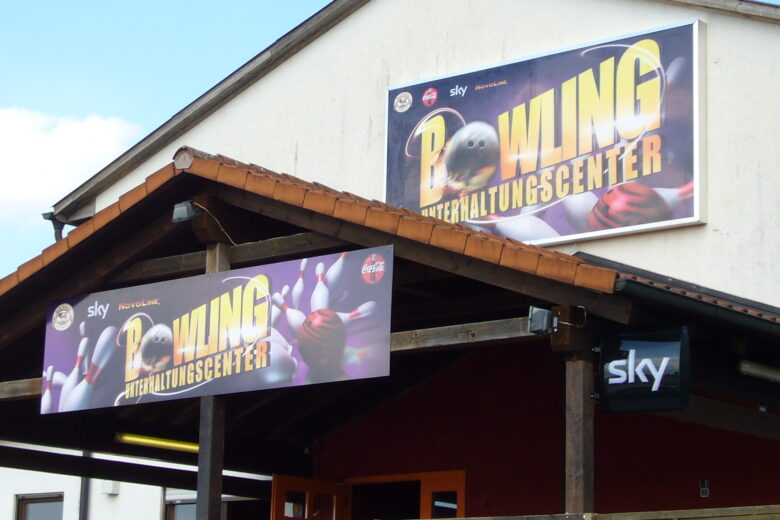 Zwei große Werbebanner für ein Bowling Unterhaltungscenter an einem Gebäude.