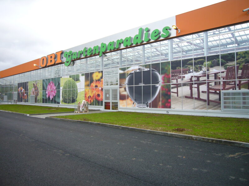 Fassade des OBI Gartenparadies mit Bildern von Pflanzen und Gartenmöbeln.