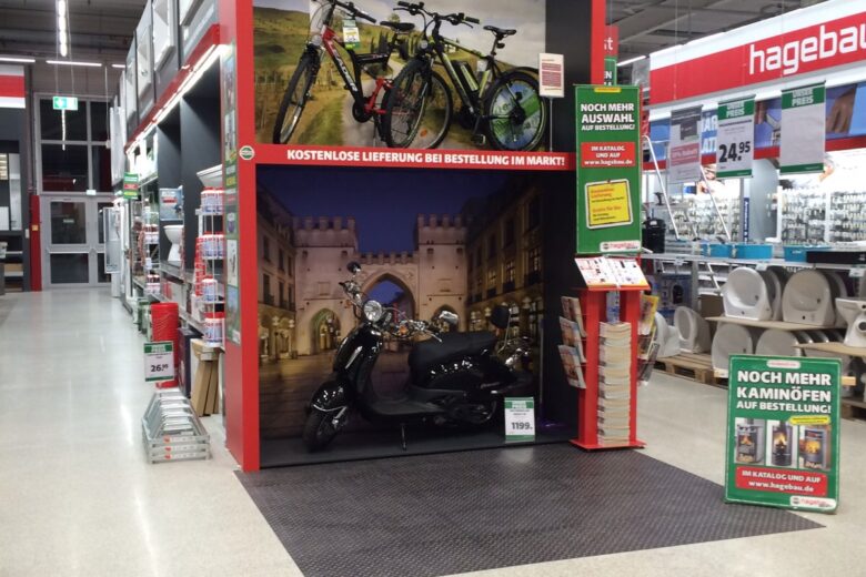 Verkaufsstand bei Hagebau mit Fahrrädern und einem Motorrad in einer Verkaufsumgebung.