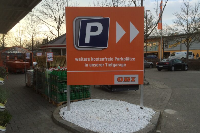 Schild mit Parkplatzinformation und OBI-Logo, das auf kostenfreie Parkplätze hinweist.