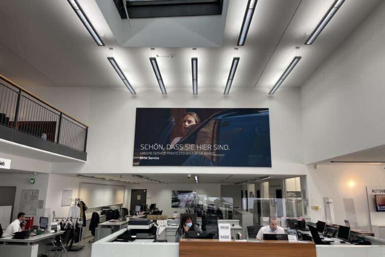 Ein Empfangsbereich mit einem großen Werbebanner und Mitarbeitern am Empfangstresen.