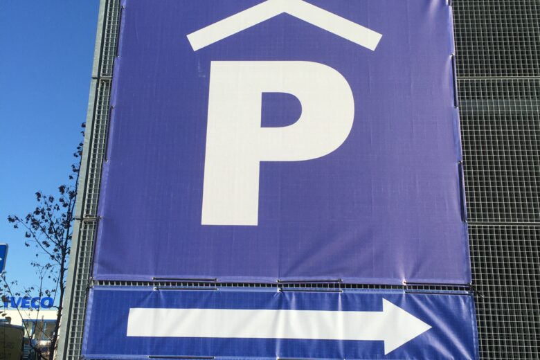 Ein großes, blaues Schild mit einem weißen 'P' für Parkplatz und einem Pfeil nach rechts.