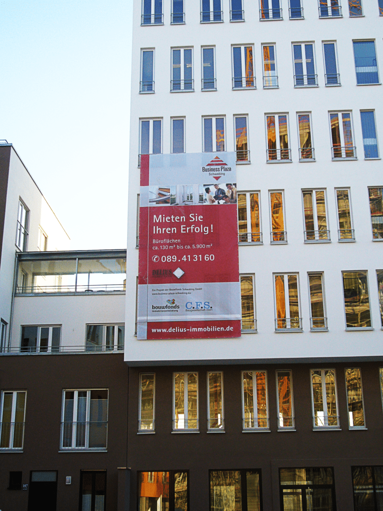 Großes Werbebanner an einem Gebäude mit Informationen zur Immobilienvermietung in München.