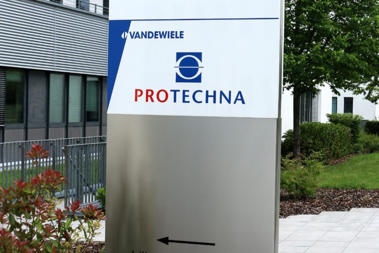 Firmenschild von PROTECHNA mit Logo und Adresse an einem modernen Gebäude.